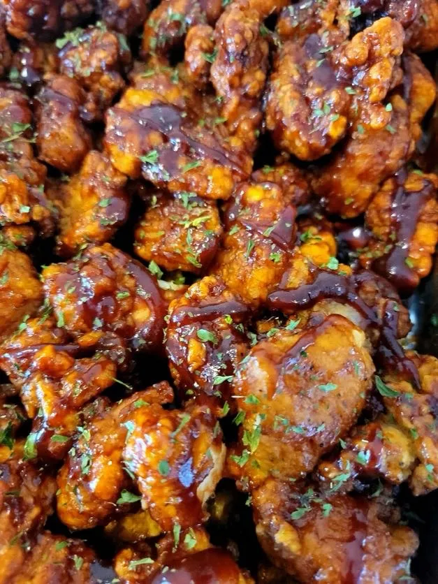 Close-up of glazed barbecue chicken wings garnished with fresh herbs