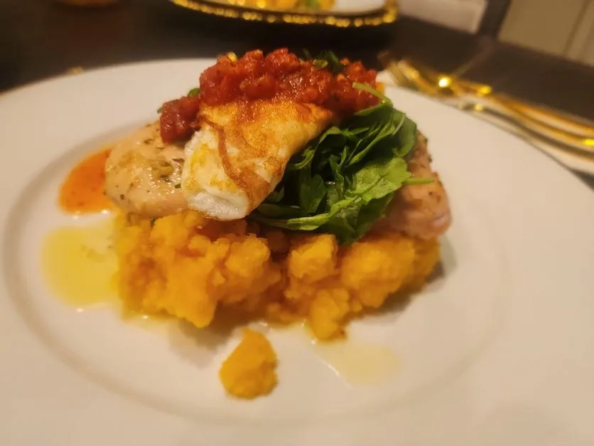 Plated pan-seared fish over butternut squash purée with greens